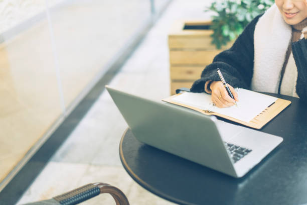 istock young woman making notes with laptop in sidewalk cafe 878859854