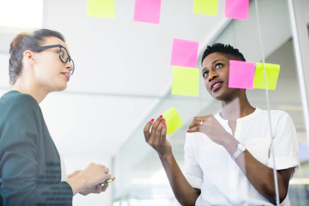 istock Businesswomen discussing over adhesive notes 878860002