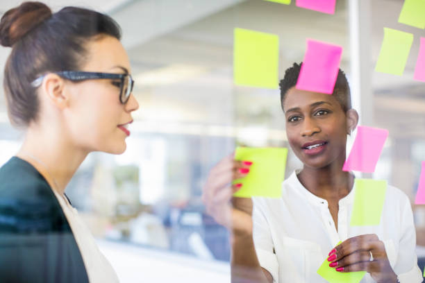 istock Businesswomen discussing over adhesive notes 878860118
