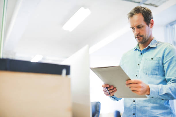 istock Businessman reading file in creative office 878860744