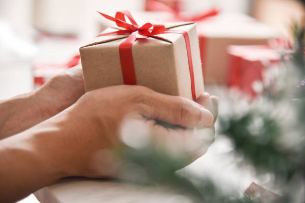 istock Male hands holding a brown present box. 878863468