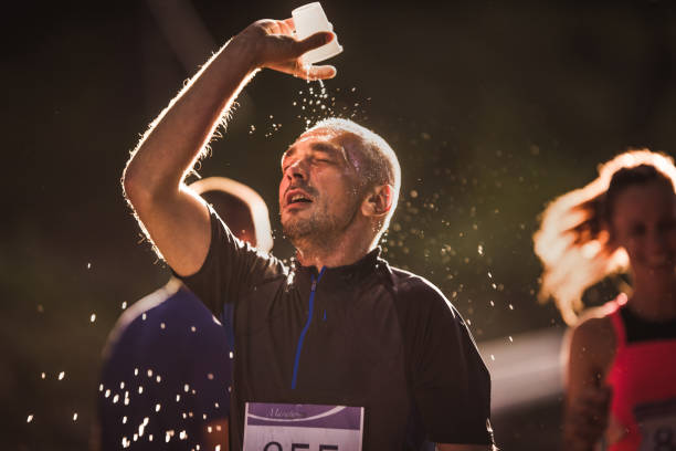 Exhausted runner pouring water on his head during marathon race in nature.