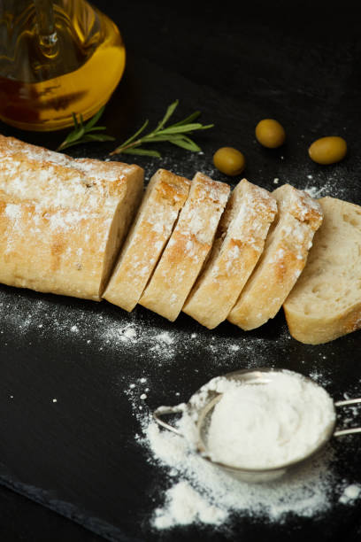 istock Ciabatta bread sliced, olives, olive oil and flour on a black stone surface 878871824