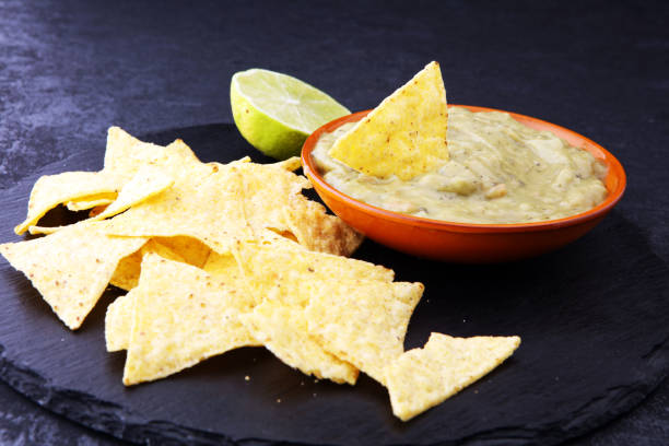 istock Bowl of guacamole with tortilla chips on dark background 878876318