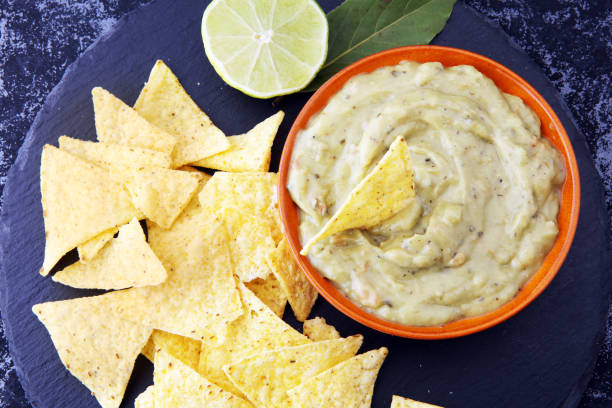 istock Bowl of guacamole with tortilla chips on dark background 878876392