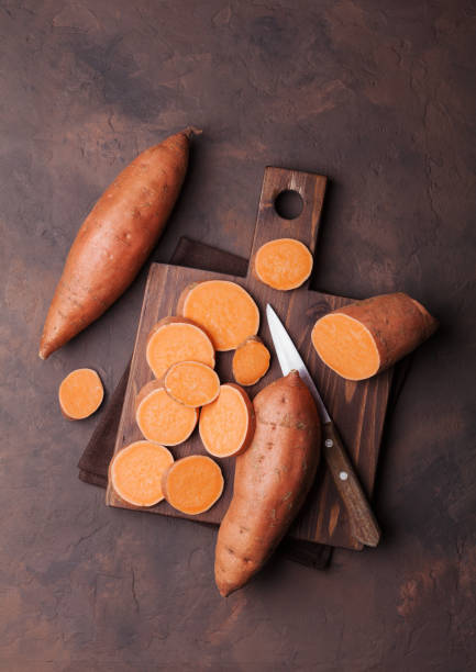 zoete aardappel op houten keuken bord van bovenaf. - zoete aardappel fotos stockfoto's en -beelden