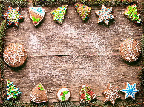 Gingerbread Christmas cookies pine branches frame on wooden table with sugar