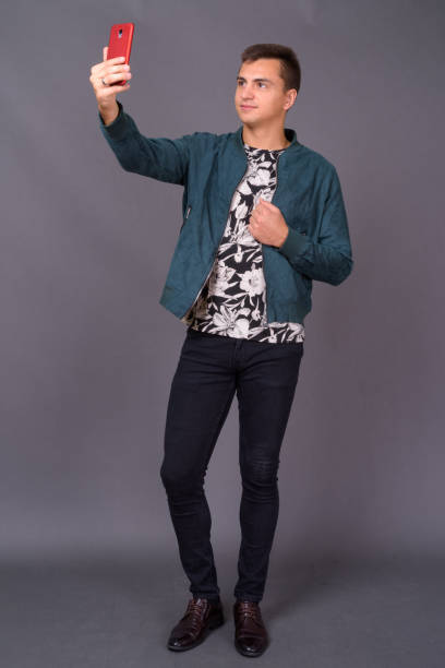 istock Young handsome man wearing floral patterned shirt and blue jacket against gray background 878885674