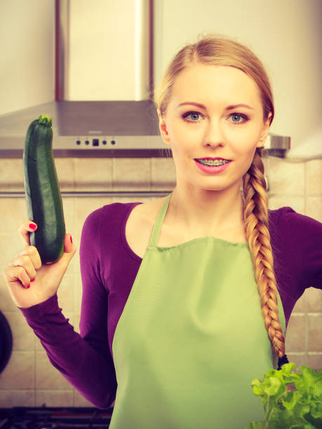 istock Woman in kitchen holds zucchini vegetable 878887808