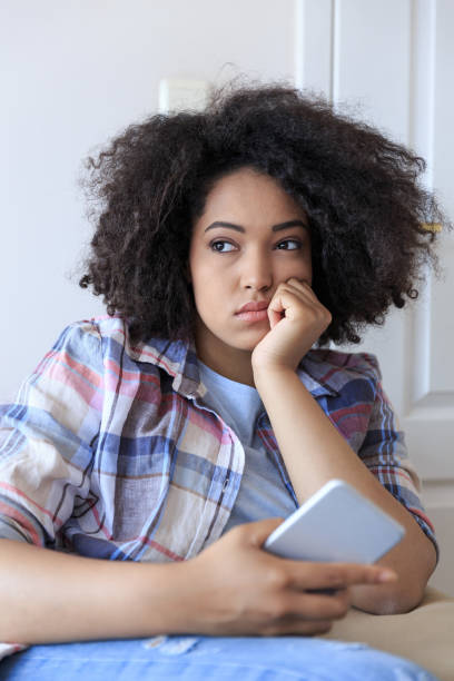 istock Young woman sitting at home and using smart phone 878888208