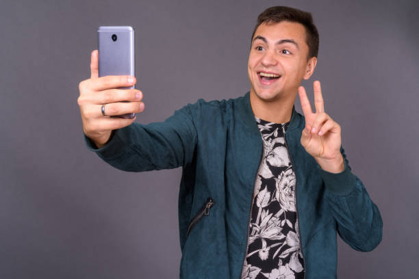 istock Young handsome man wearing floral patterned shirt and blue jacket against gray background 878888380