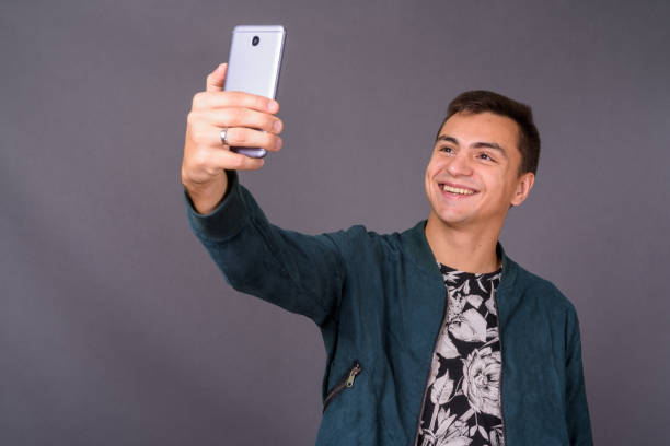 istock Young handsome man wearing floral patterned shirt and blue jacket against gray background 878888384