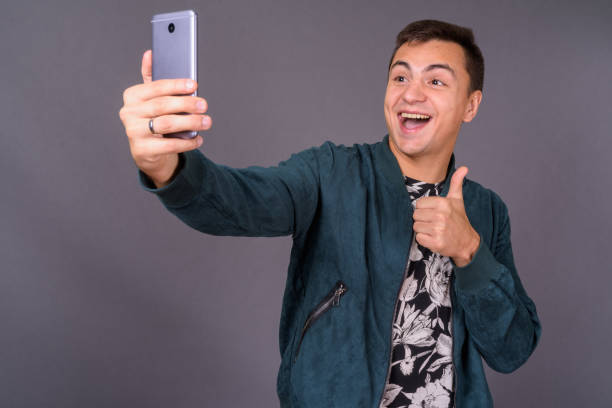 istock Young handsome man wearing floral patterned shirt and blue jacket against gray background 878888408