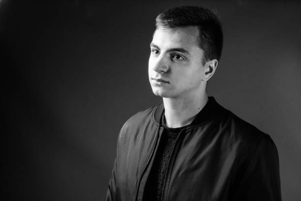 istock Young handsome man wearing jacket against gray background in black and white 878894370