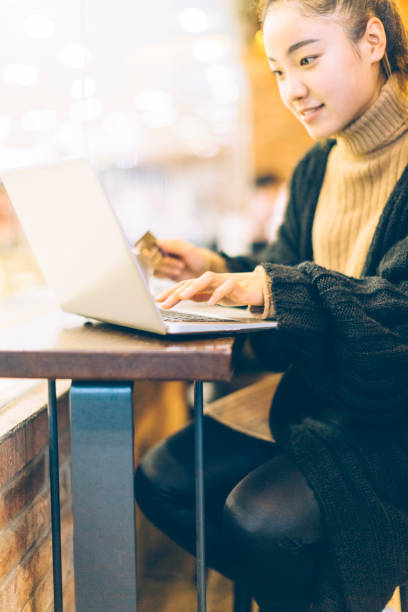 istock young woman using credit card and laptop in cafe 878894396