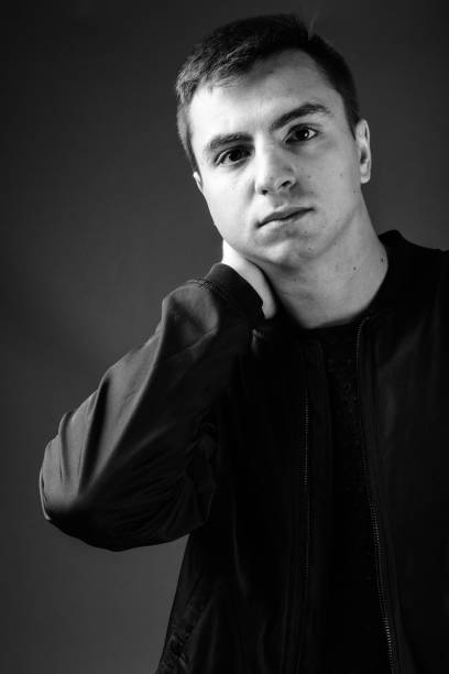 istock Young handsome man wearing jacket against gray background in black and white 878894454