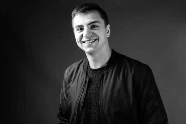istock Young handsome man wearing jacket against gray background in black and white 878894524