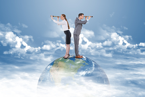 Businessman and businesswoman searching through telescope on top of the world