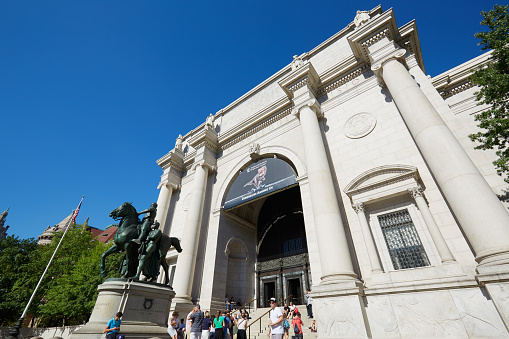 New York - September 13, 2016: American Museum of Natural History building facade and Theodore Roosevelt statue with people in a sunny day, clear blue sky on September 13, 2016 in New York. This is one of the largest museum of natural history of the world.