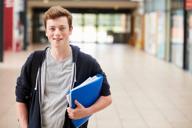 Portrait Of Male Student Standing In College Building Portrait Of Male Student Standing In College Building 16 17 years stock pictures, royalty-free photos & images
