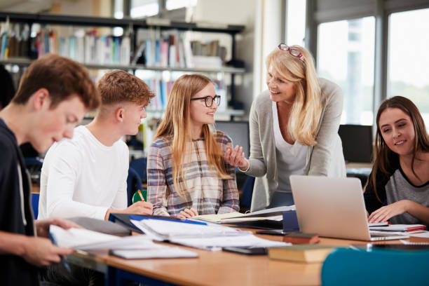 istock Female Teacher Working With College Students In Library 878922430