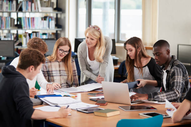 istock Female Teacher Working With College Students In Library 878922432
