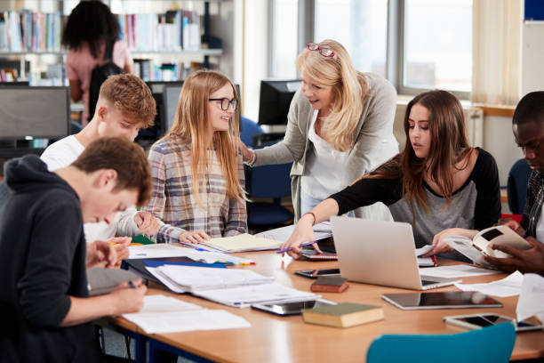 istock Female Teacher Working With College Students In Library 878922436