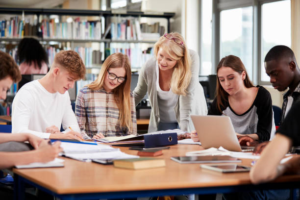 istock Female Teacher Working With College Students In Library 878922620