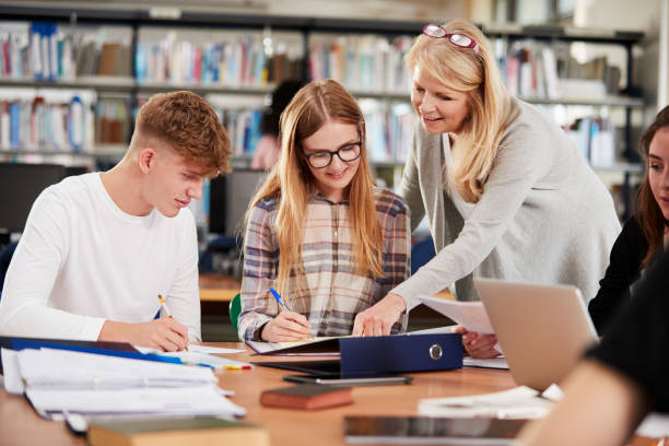 istock Female Teacher Working With College Students In Library 878928836