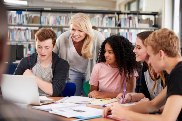 istock Female Teacher Working With College Students In Library 878930952