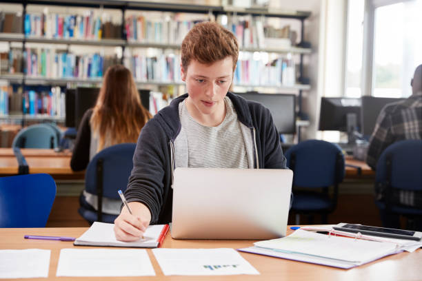 istock Male Student Working At Laptop In College Library 878931728