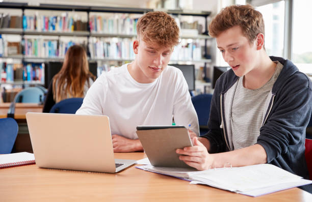 istock Two Male College Students Collaborating On Project In Library 878931778