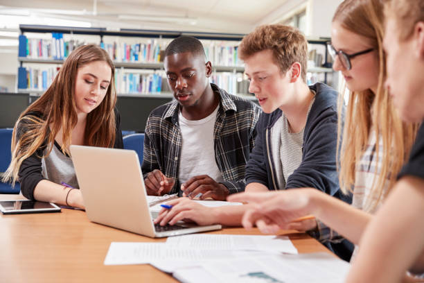 istock Group Of College Students Collaborating On Project In Library 878931912