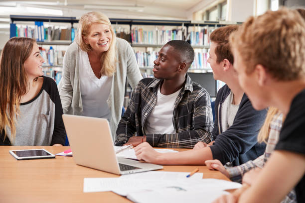 istock Female Teacher Working With College Students In Library 878934124