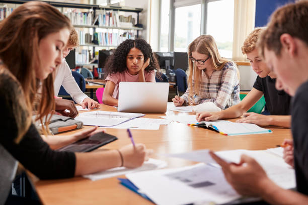 istock Group Of College Students Working Around Table In Library 878934306