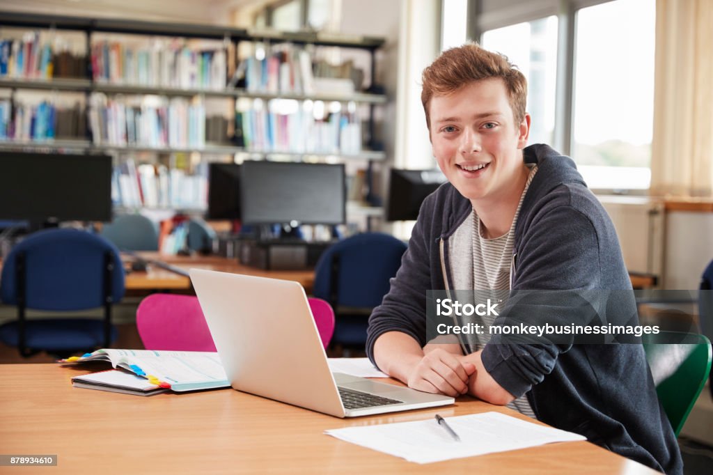 Retrato de estudante do sexo masculino trabalhando no Laptop na biblioteca da faculdade - Foto de stock de Estudante royalty-free