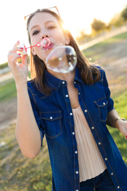 istock Beautiful young woman making soap bubbles in the park. 878961868