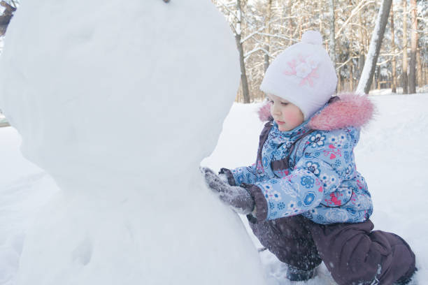 istock Little girl making snowman from natural snow 878961896