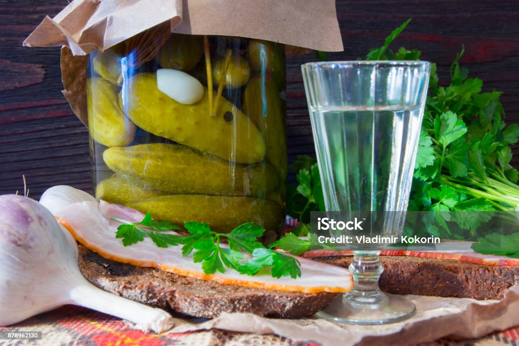Traditional Ukrainian and Russian appetizer when dining. Food when drinking alcohol. Vodka and sandwiches with bacon, garlic and pickles. Moonshine - Alcohol Stock Photo