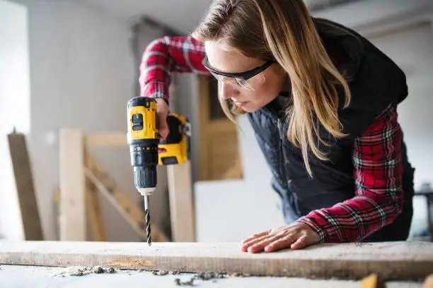 Photo of Young woman worker in the carpenter workroom.