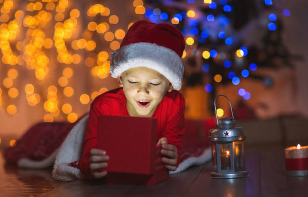 istock Cute boy opening a magical present on Christmas eve 878990828