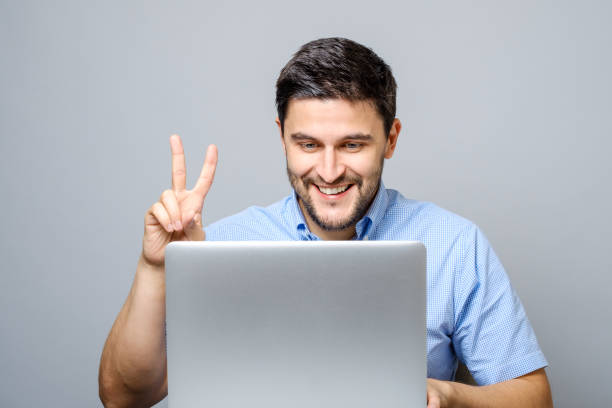 istock Happy young man video chatting on laptop computer isolated on gray background 878994368