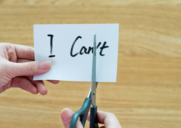 istock Woman hand holding scissors cutting word 'I can't' 878994484