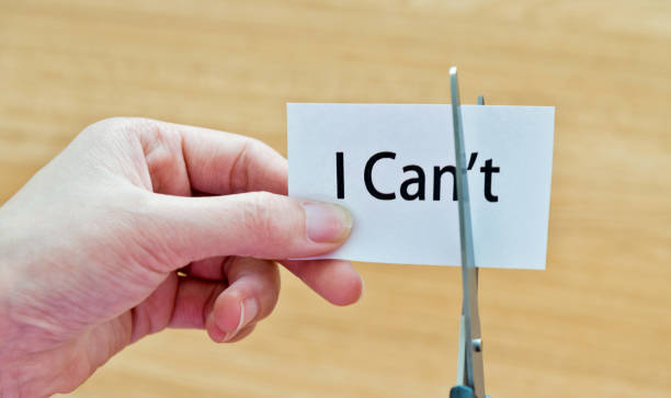 istock Woman hand holding scissors cutting word 'I can't' 878994524