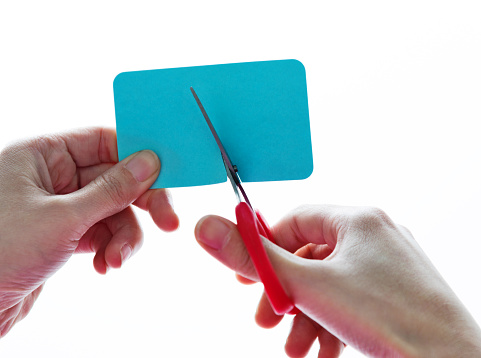 Woman hands using scissors cutting a blue paper