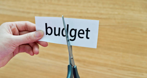 istock Human hand cutting the budget word 879004946