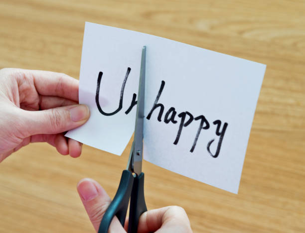 istock Human hand cutting word on paper unhappy become happy 879004982