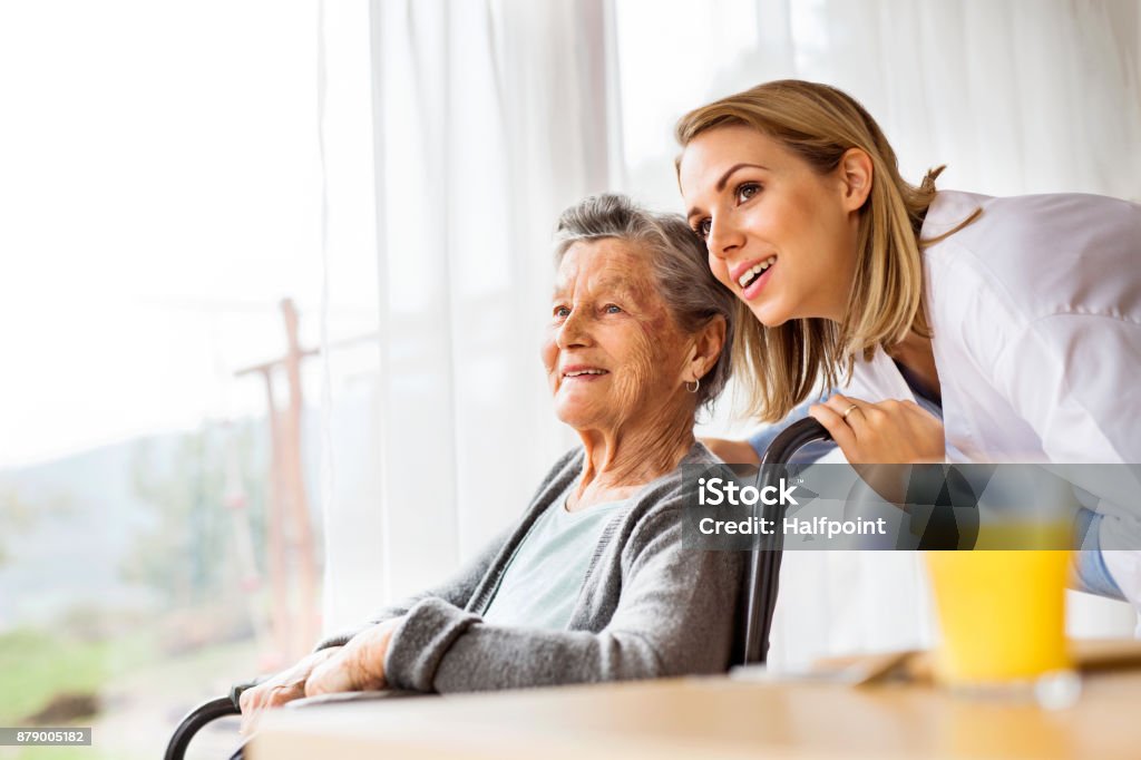 Visitante de saúde e uma mulher sênior durante visita em casa. - Foto de stock de Terceira idade royalty-free