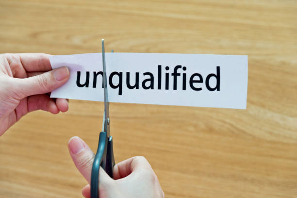 istock Human hand cutting word on paper unqualified become qualified 879007812