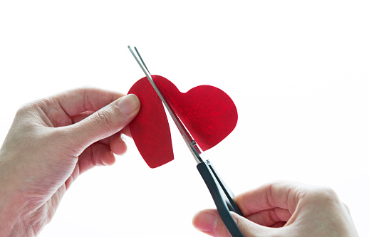 Human hand holding Scissors cutting heart shape